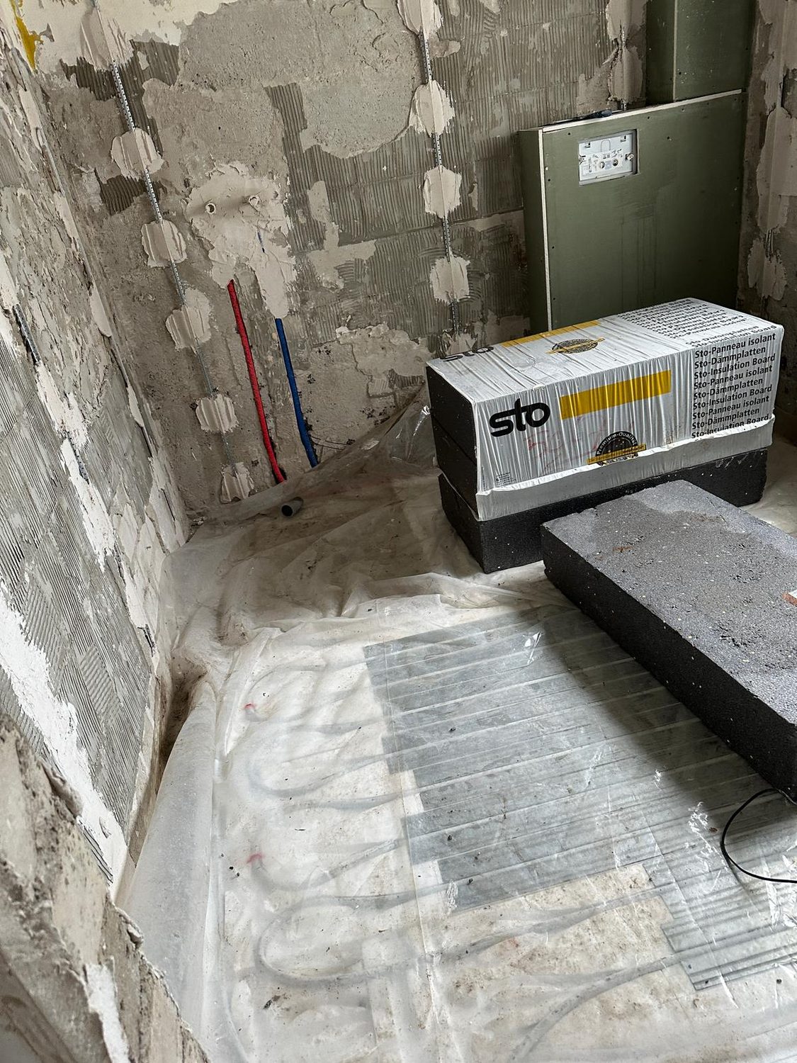 Bad im Rückbau mit freigelegten Leitungen und bereitgestellten Dämmplatten