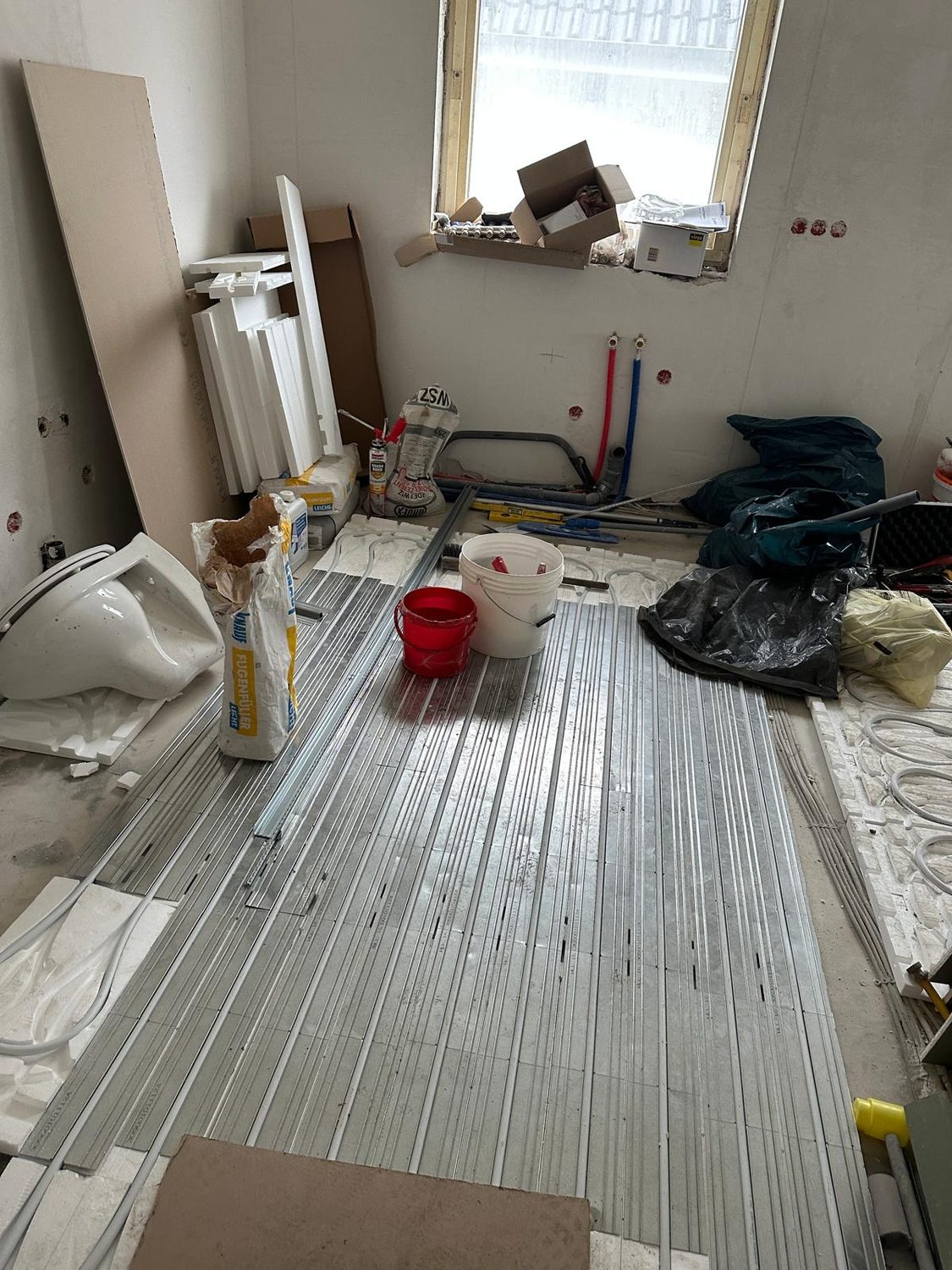Fußbodenheizung im Badezimmer verlegt, Sanitärobjekte stehen bereit