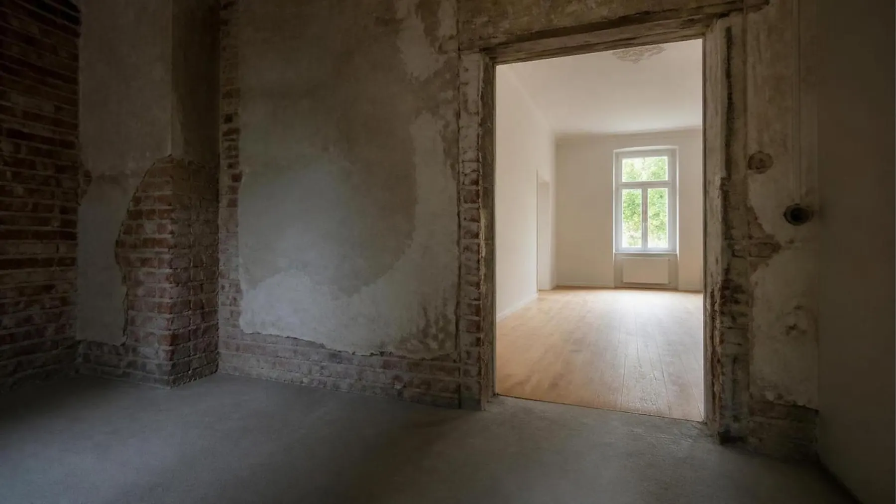 Altbauwohnung in der Sanierung: vorne der Rohbau, durch die Tür der fertig sanierte Raum