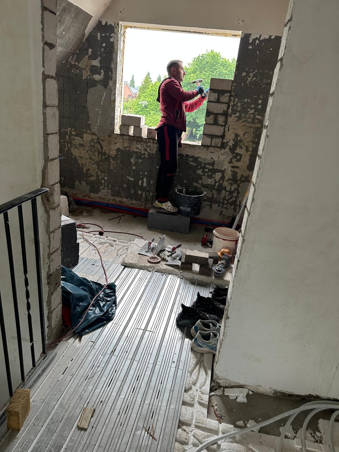 Handwerker mauert eine Fensteröffnung im Obergeschoss zu